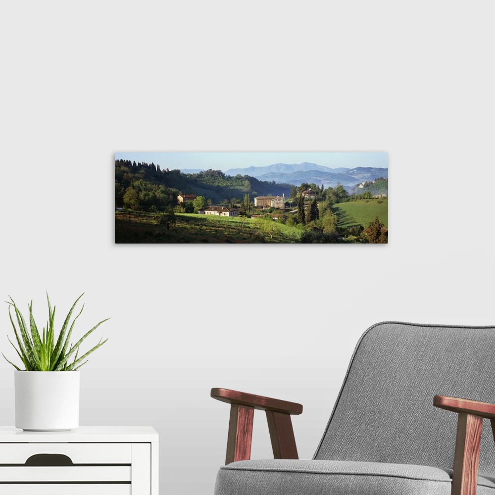 A modern room featuring Giant, landscape photograph of rolling green hills and tress surrounding several houses in Marche...