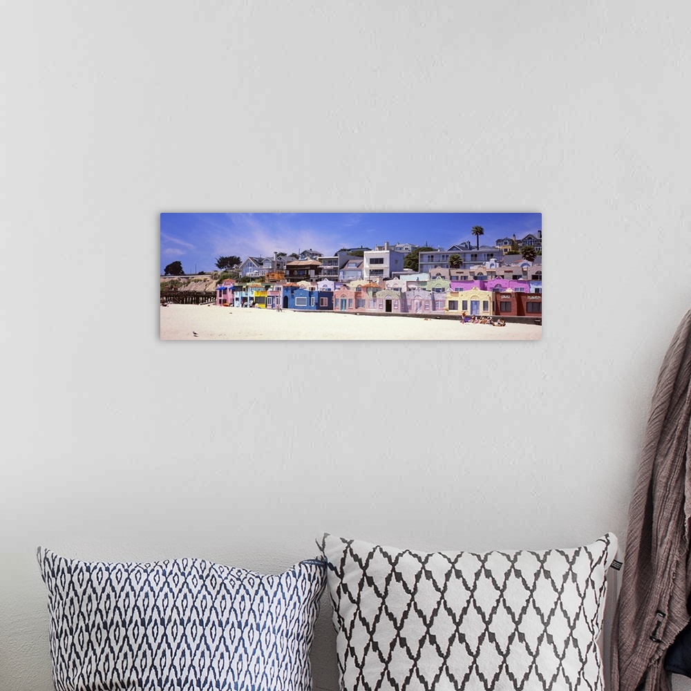 A bohemian room featuring Colorful buildings along a sandy boardwalk overlooking the water.