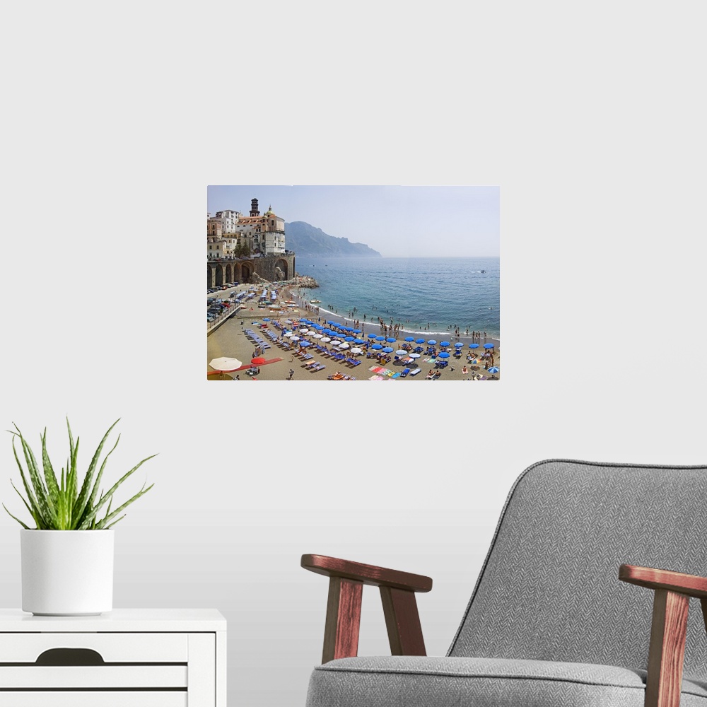 A modern room featuring Summer scene on the beach with lots of parasols and swimmers, and historic buildings on the edge ...