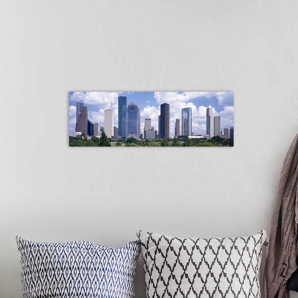 A bohemian room featuring Giant, landscape wall picture of the Houston skyline, under a bright blue sky with many fluffy cl...