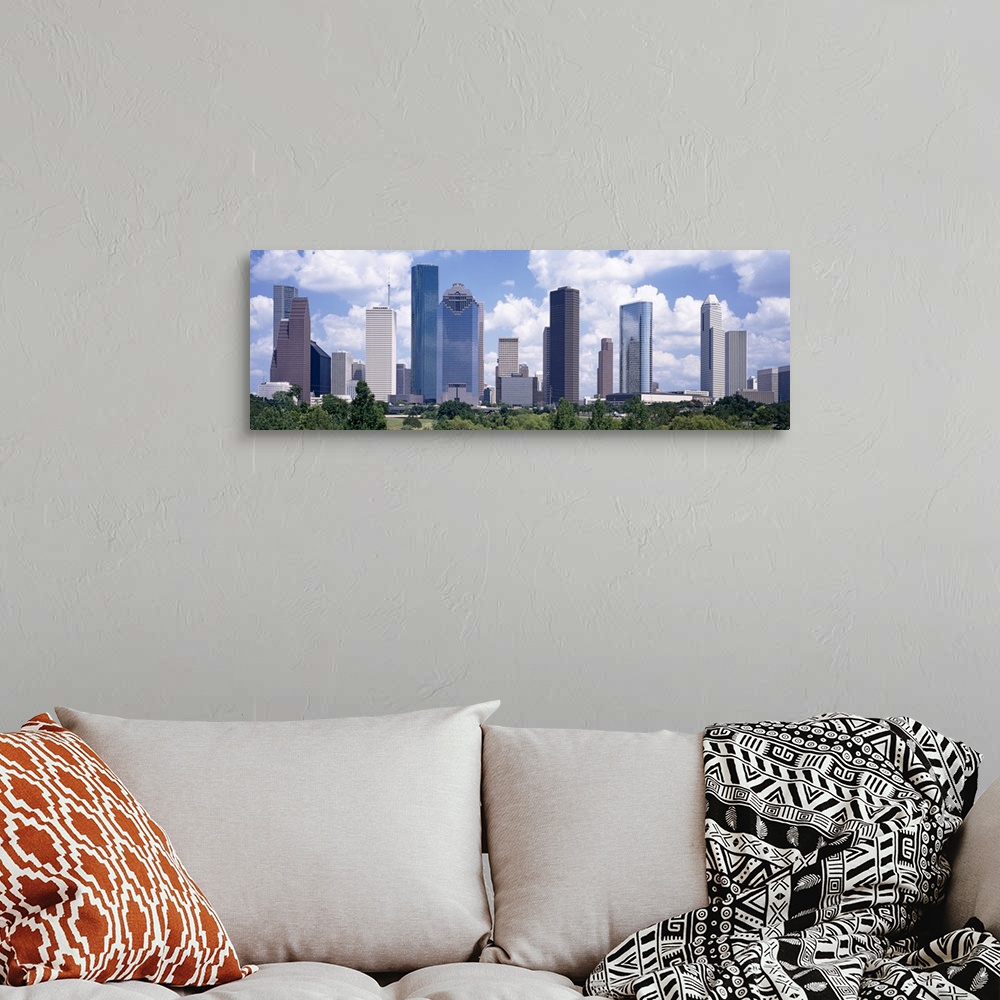 A bohemian room featuring Giant, landscape wall picture of the Houston skyline, under a bright blue sky with many fluffy cl...