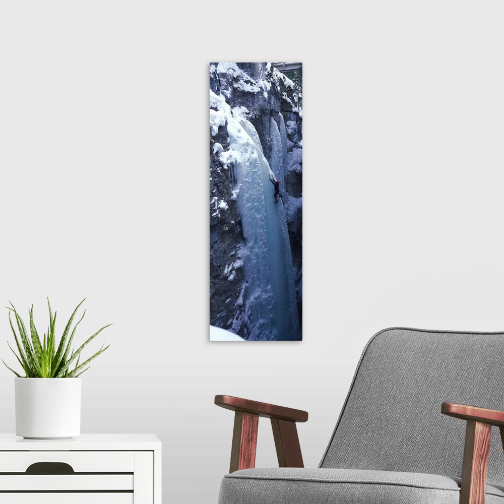 A modern room featuring Vertical panoramic photograph of climber on ice covered rock.