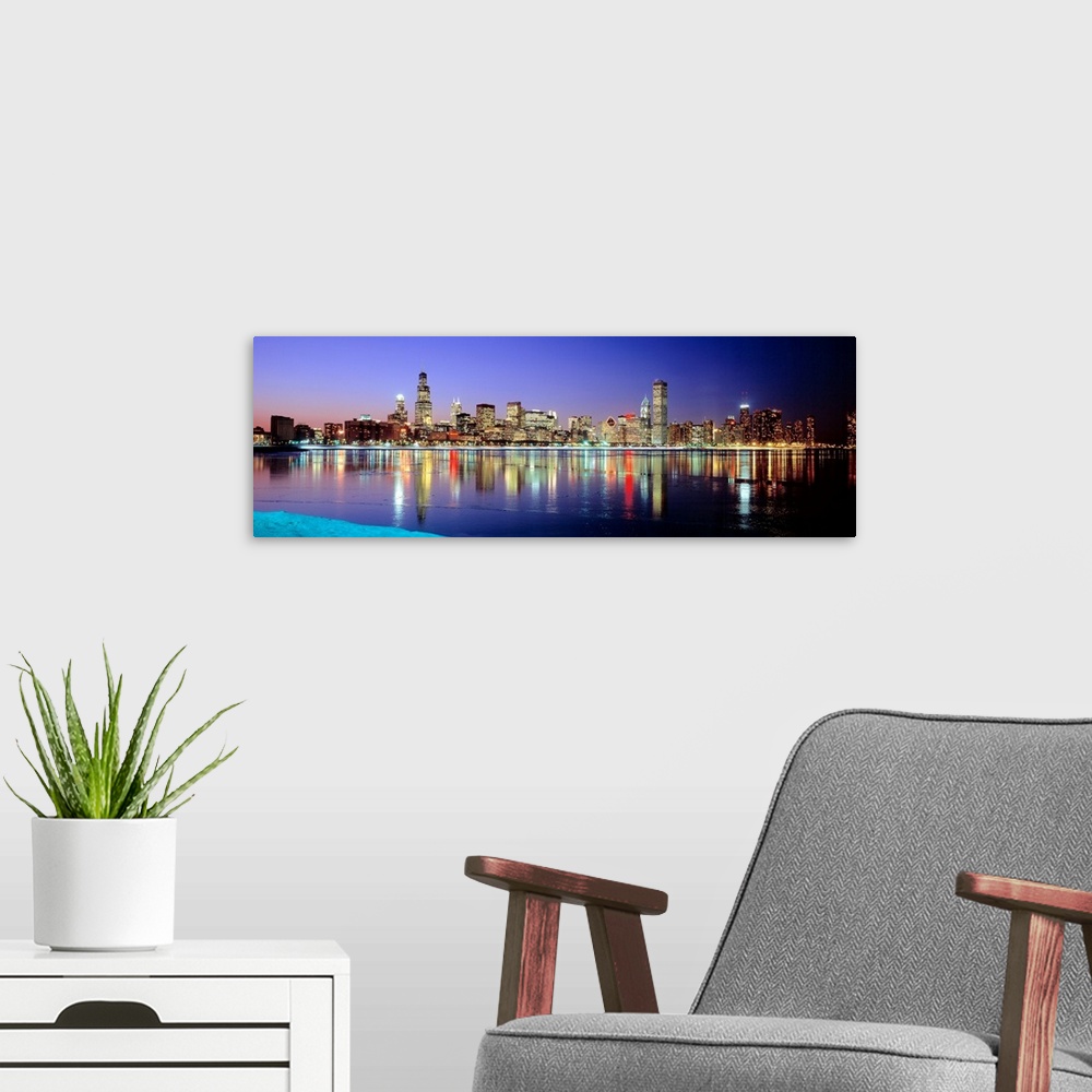 A modern room featuring Panoramic photographic canvas of a cityscape illuminated with colored lights reflected perfectly ...
