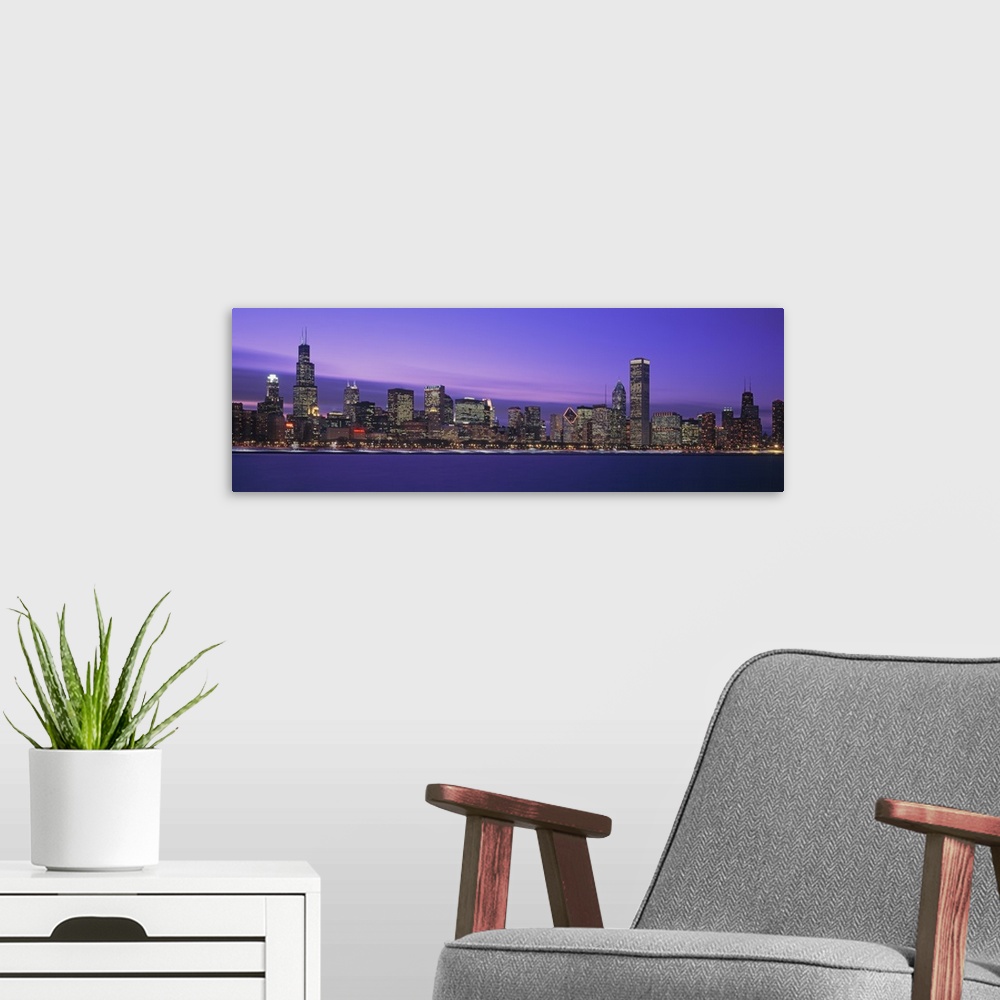 A modern room featuring Oversized, horizontal, panoramic photograph of lit skyscrapers of the Chicago skyline at night.