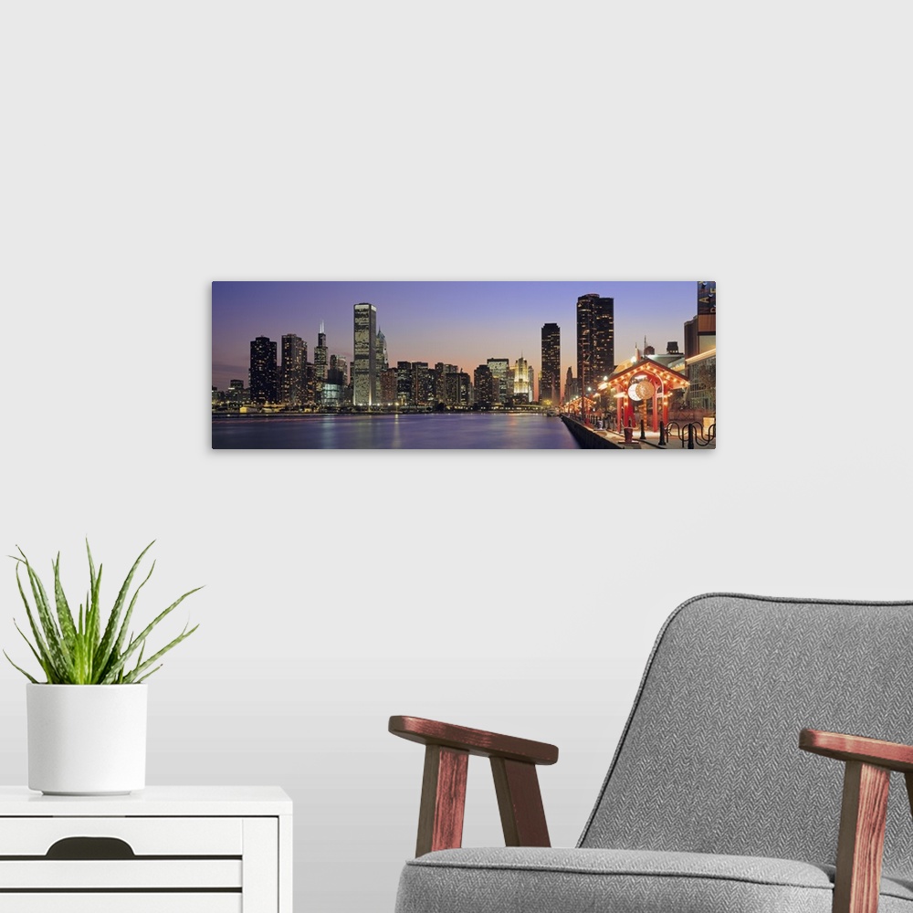 A modern room featuring Panoramic cityscape of Chicago at the edge of Lake Michigan at dusk, with the skyscrapers lit up ...