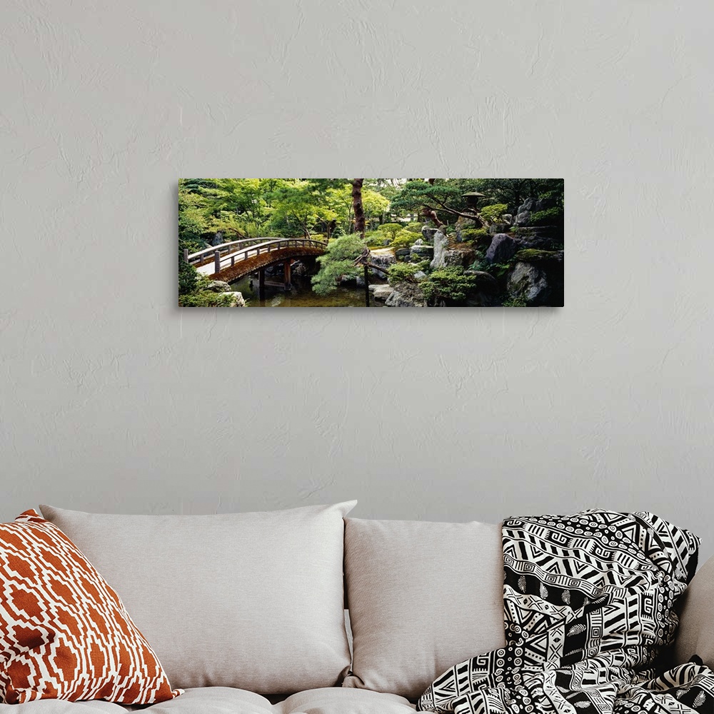 A bohemian room featuring Panoramic photo on canvas of a bridge leading over a river with a garden on the right.