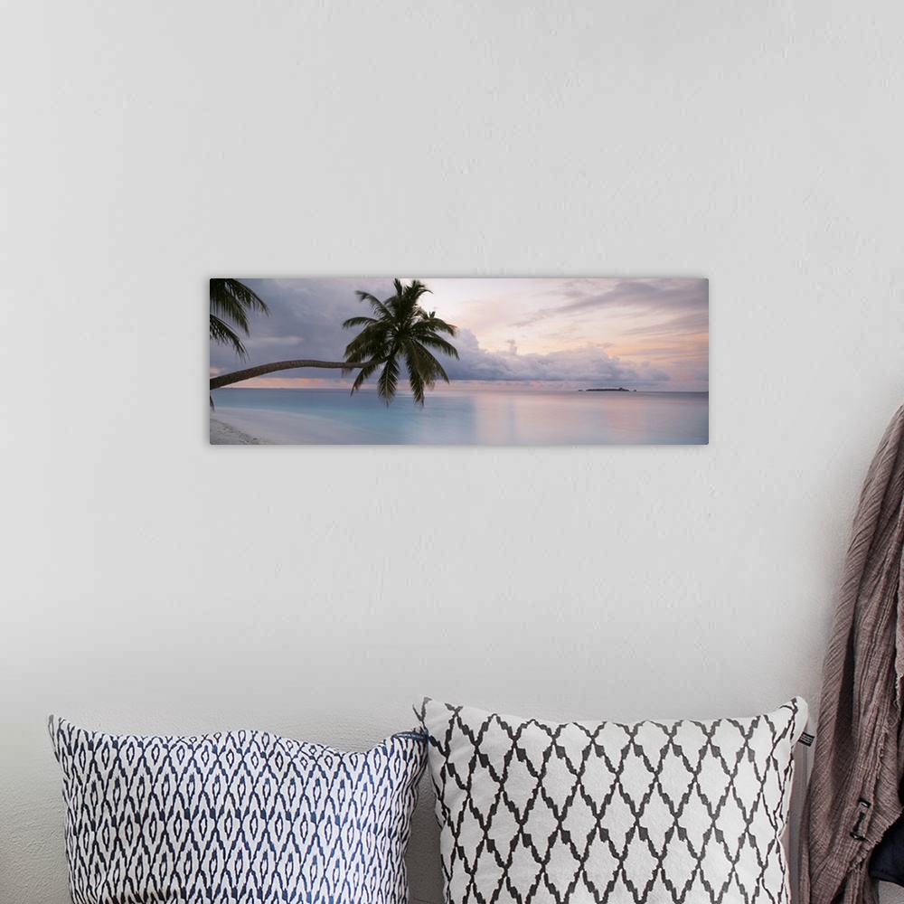 A bohemian room featuring Large art piece of the still ocean with a cooler toned sky above. Palm trees float over the sand ...