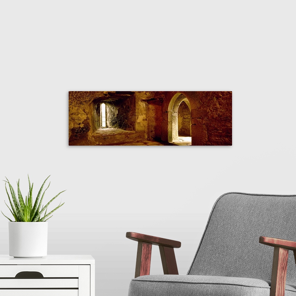 A modern room featuring Panoramic photograph of the inside of an old stone palace with arched doorways.