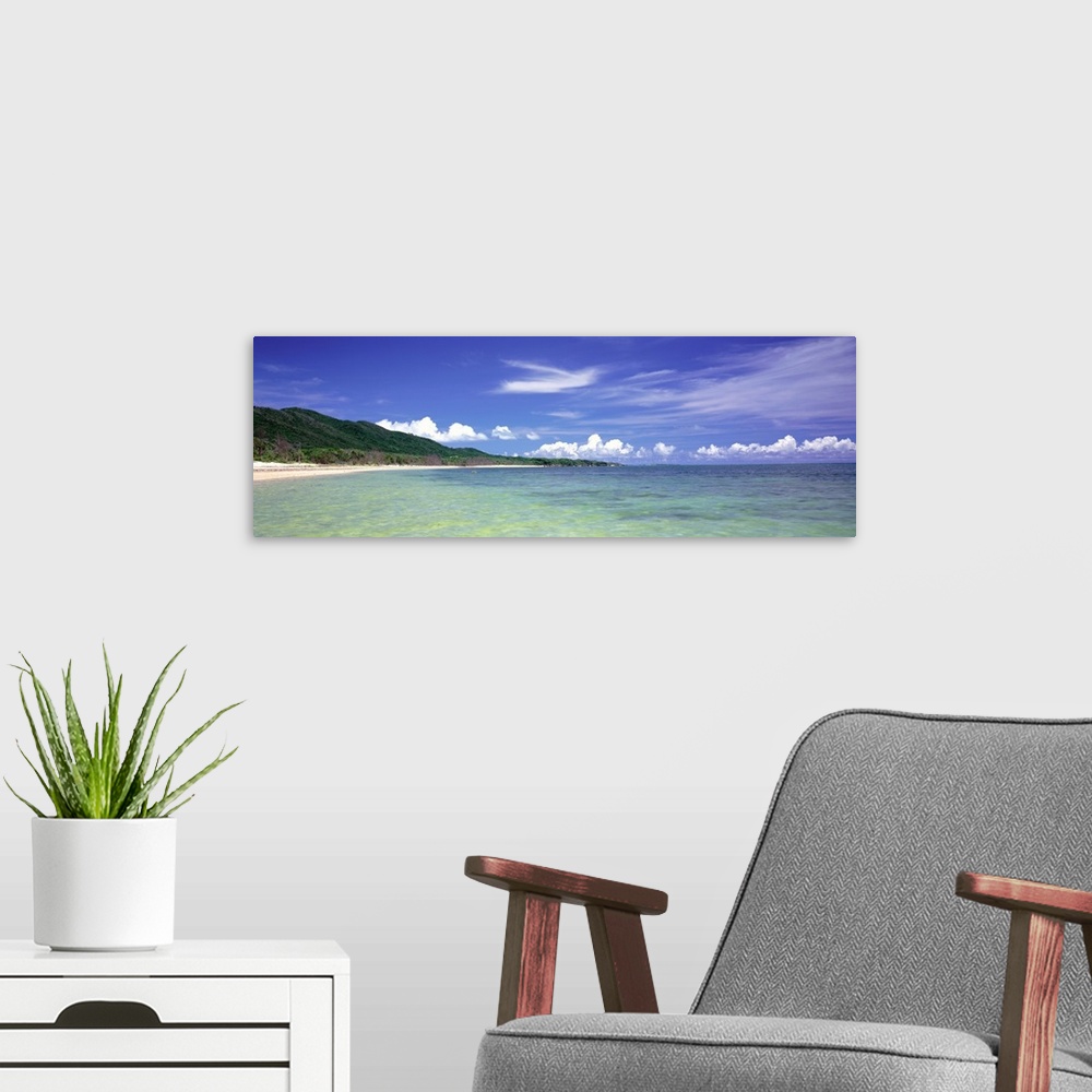 A modern room featuring Panoramic photograph of ocean with shoreline and grass covered mountains in the distance under a ...