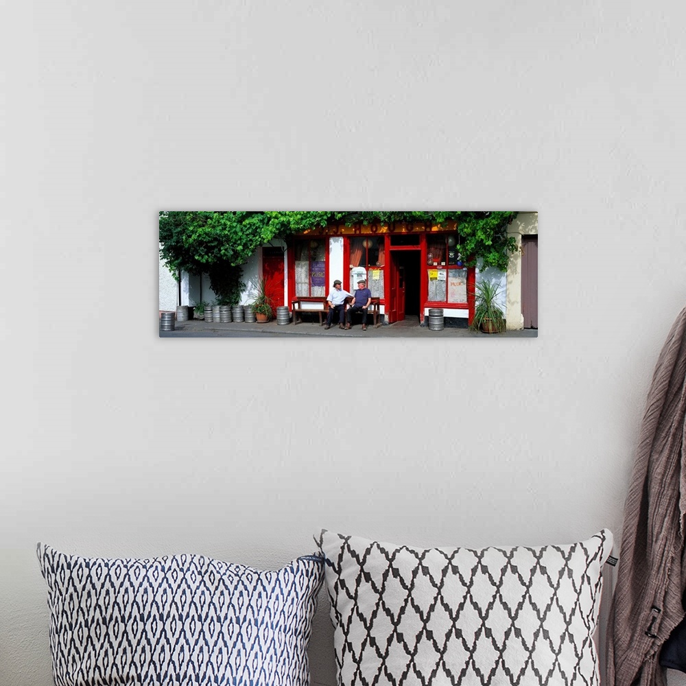 A bohemian room featuring Panoramic picture snapped of two men as they sit on a bench outside a bar in Ireland. The front o...
