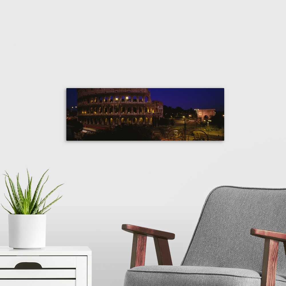A modern room featuring Wide angle photograph of the Coliseum, lit up at night, in Rome, Italy.