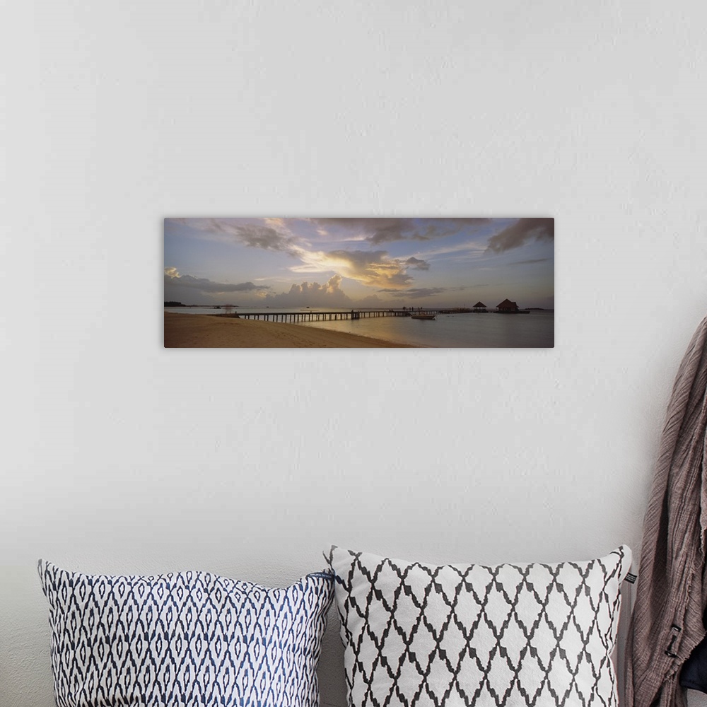 A bohemian room featuring Panoramic photograph of pier stretching into ocean from the beach under a cloudy sky at dusk.