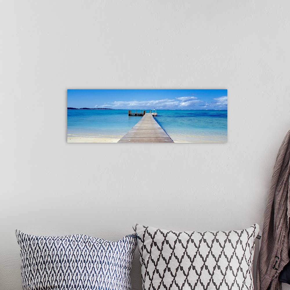 A bohemian room featuring Panoramic photograph of pier stretching into the sea off of a sandy beach.  There is a small wood...