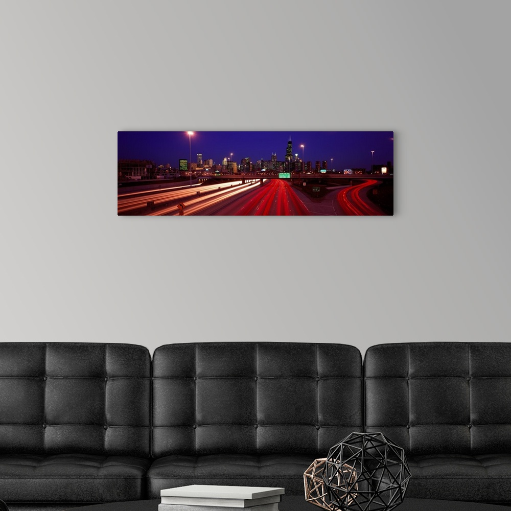 A modern room featuring Panoramic photograph of highway filled with light trails with lit up city skyline in the distance...