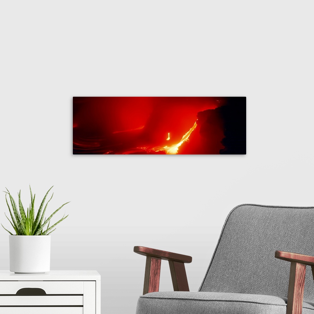 A modern room featuring Glowing panoramic photograph of lava flowing from domed mountain.