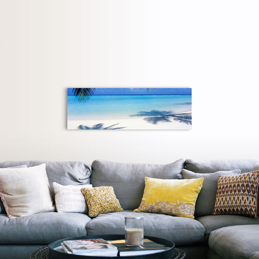A farmhouse room featuring Panoramic landscape photograph of a tropical beach with palm trees casting shadows in the sand.