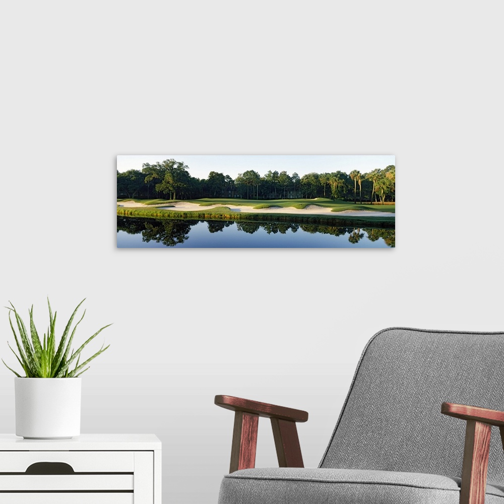A modern room featuring Reflection of an urban forest in still waters at the edge of a sand trap in a Southern US town.