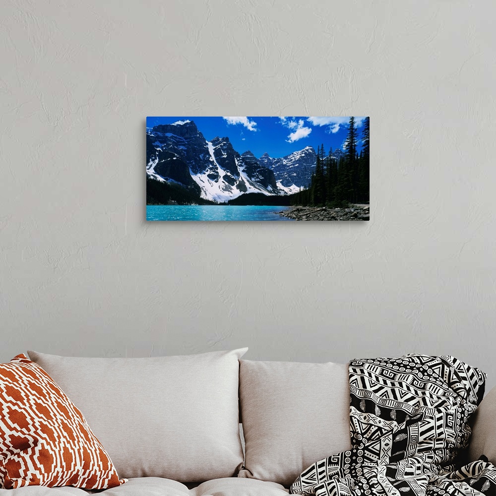 A bohemian room featuring A landscape photograph of snow covered mountains surround a lake on this horizontal wall art.
