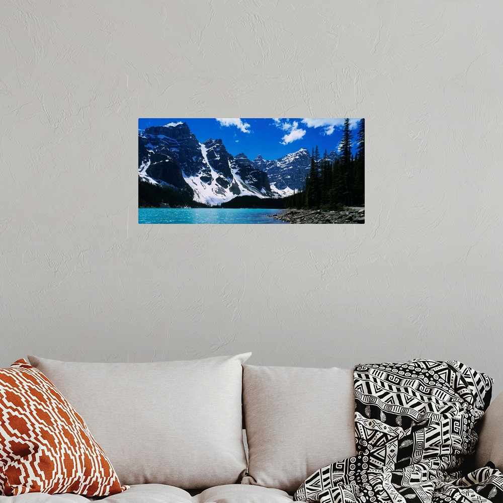 A bohemian room featuring A landscape photograph of snow covered mountains surround a lake on this horizontal wall art.