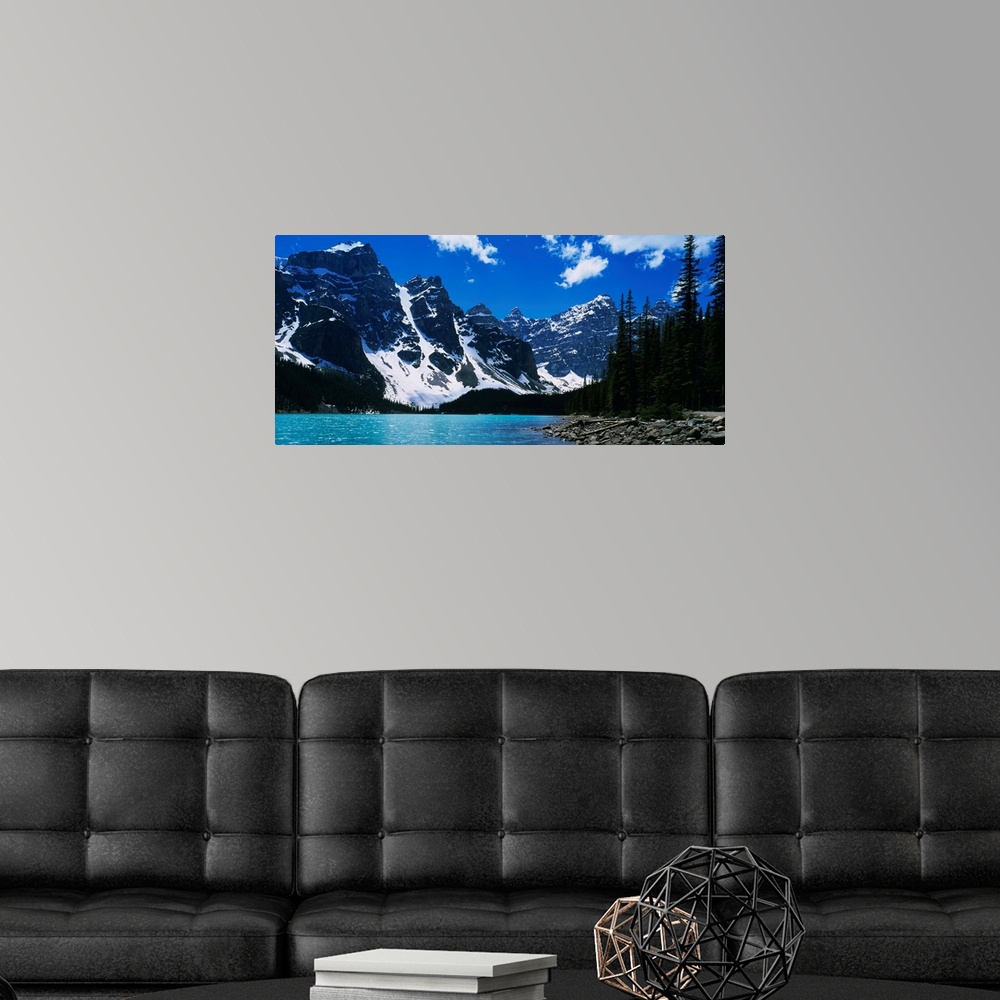 A modern room featuring A landscape photograph of snow covered mountains surround a lake on this horizontal wall art.