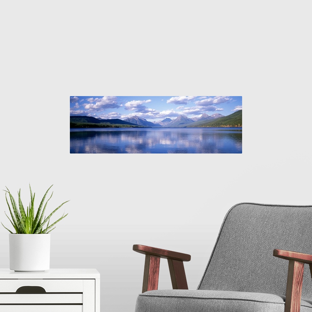 A modern room featuring Panoramic photograph Lake McDonald with small ripples in the water reflecting the mountains and t...