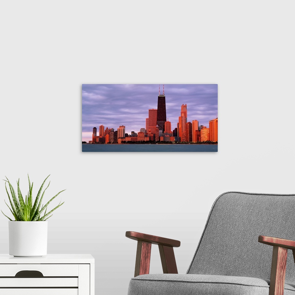 A modern room featuring This landscape wall art captures the city skyline from the lake in the fading sunlight of the eve...