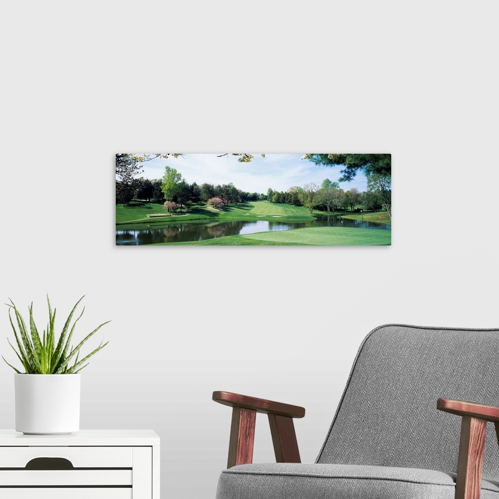 A modern room featuring Panoramic photograph of golf course featuring putting green, sand traps, and winding pond.  There...
