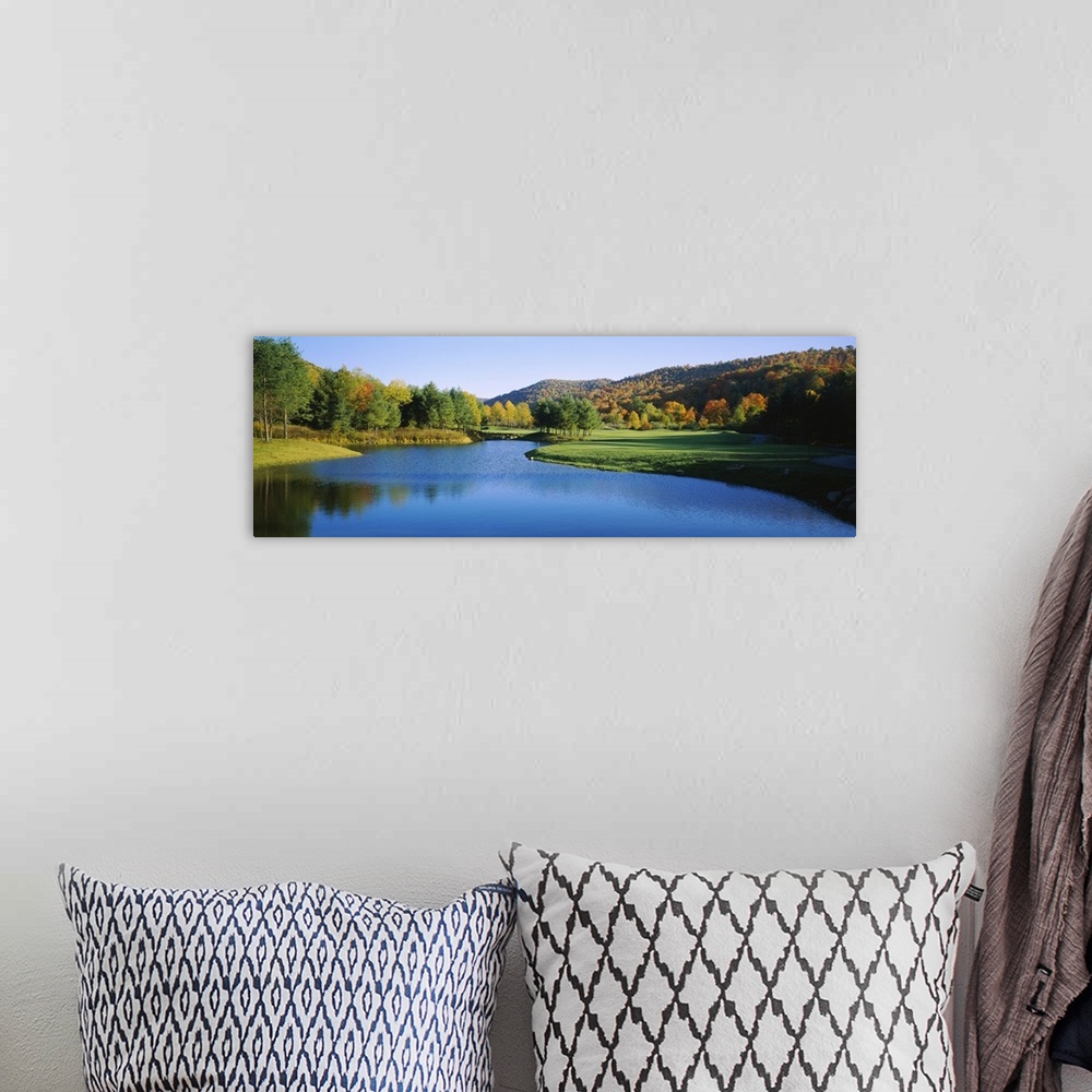 A bohemian room featuring Long horizontal canvas print of a golf course with a lake in the middle and fall foliage on rolli...