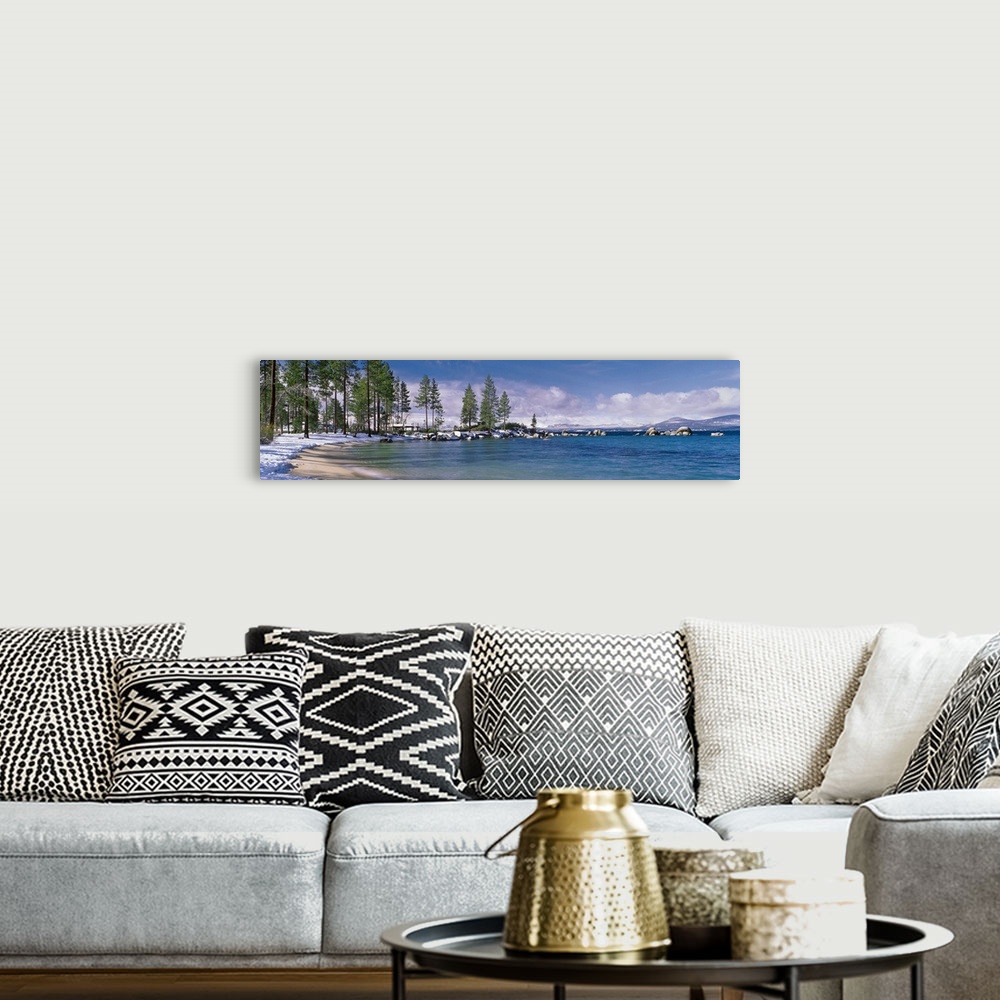 A bohemian room featuring This large panoramic piece is a photograph of the Lake Tahoe coast. Pine trees line the snow cove...