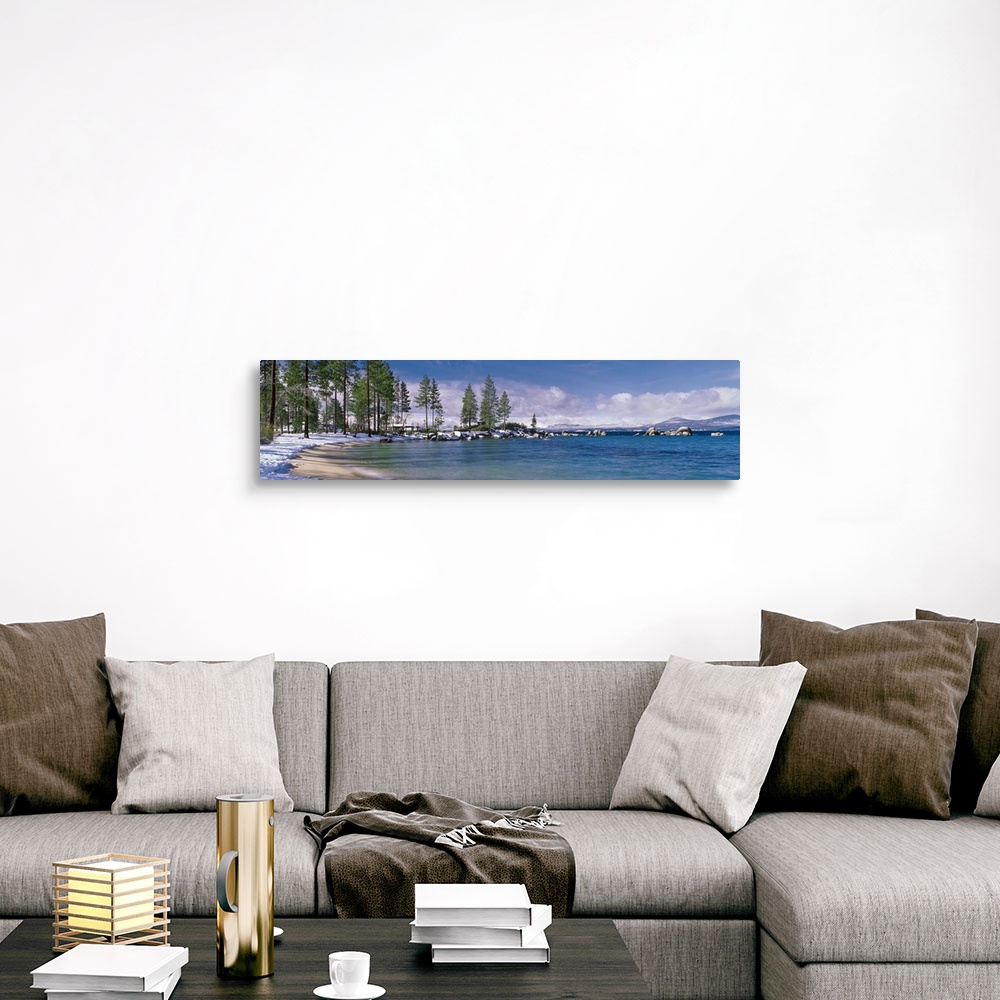 A traditional room featuring This large panoramic piece is a photograph of the Lake Tahoe coast. Pine trees line the snow cove...