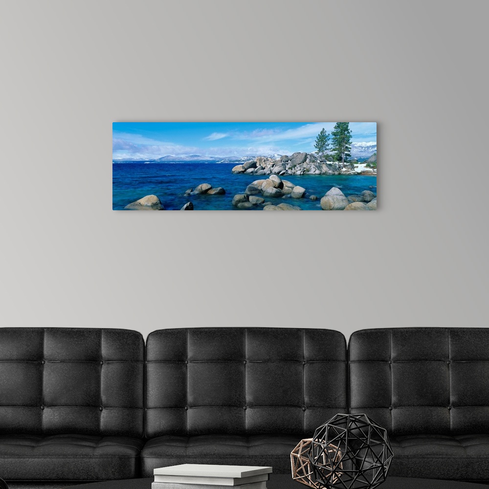 A modern room featuring A panoramic photograph taken at eye level this home wall art shows the boulder covered shores of ...