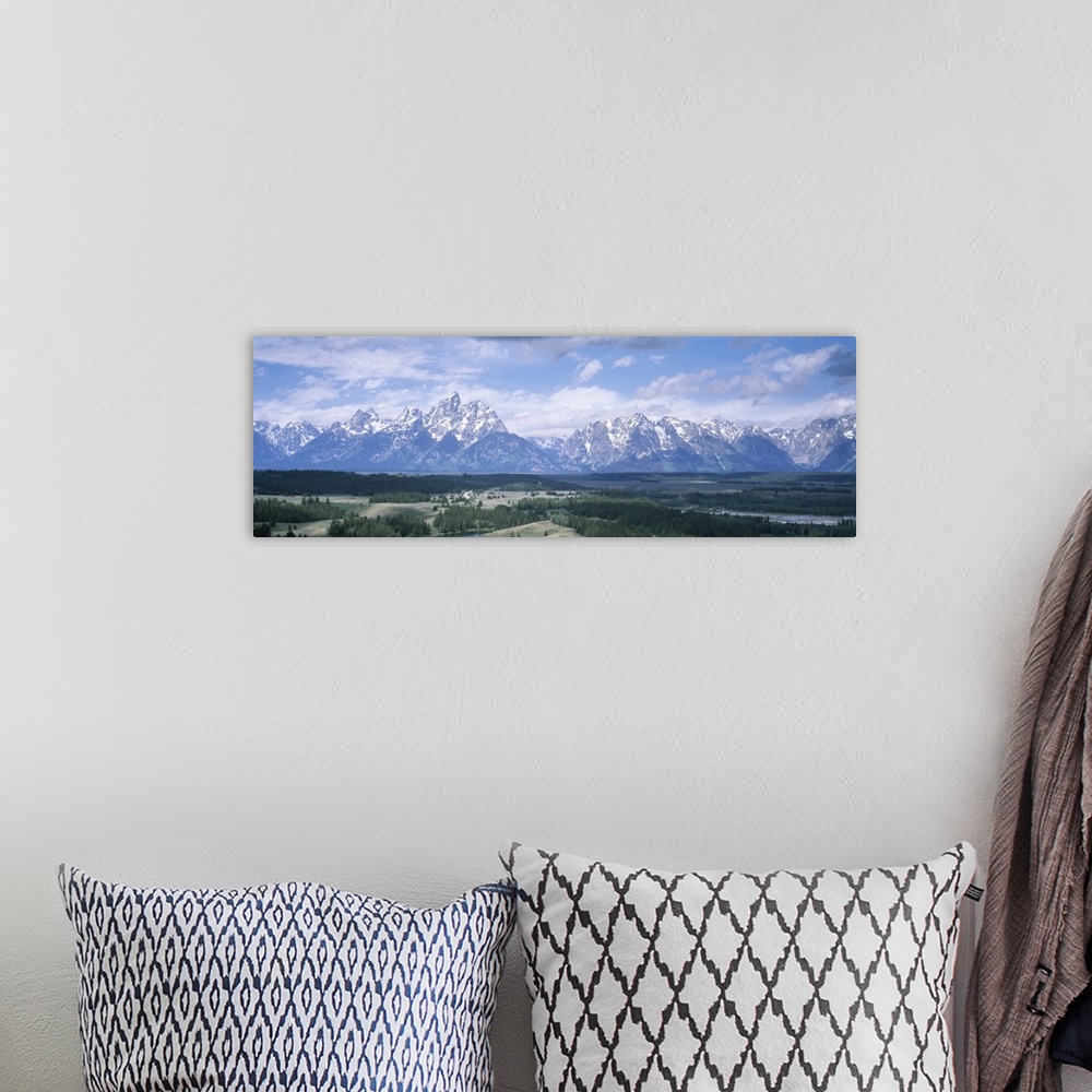 A bohemian room featuring Panoramic picture taken of an immense mountain range in Wyoming. Vast terrain covered with trees ...