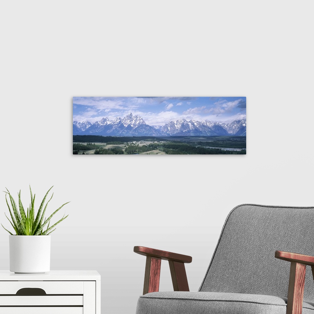 A modern room featuring Panoramic picture taken of an immense mountain range in Wyoming. Vast terrain covered with trees ...