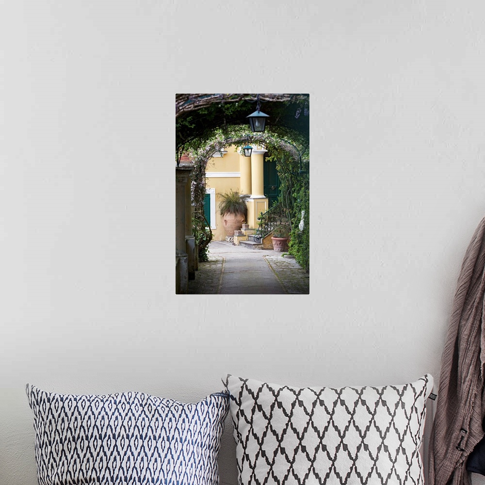 A bohemian room featuring A vertical photograph or a walkway under vine covered arches in a scenic Italian city.