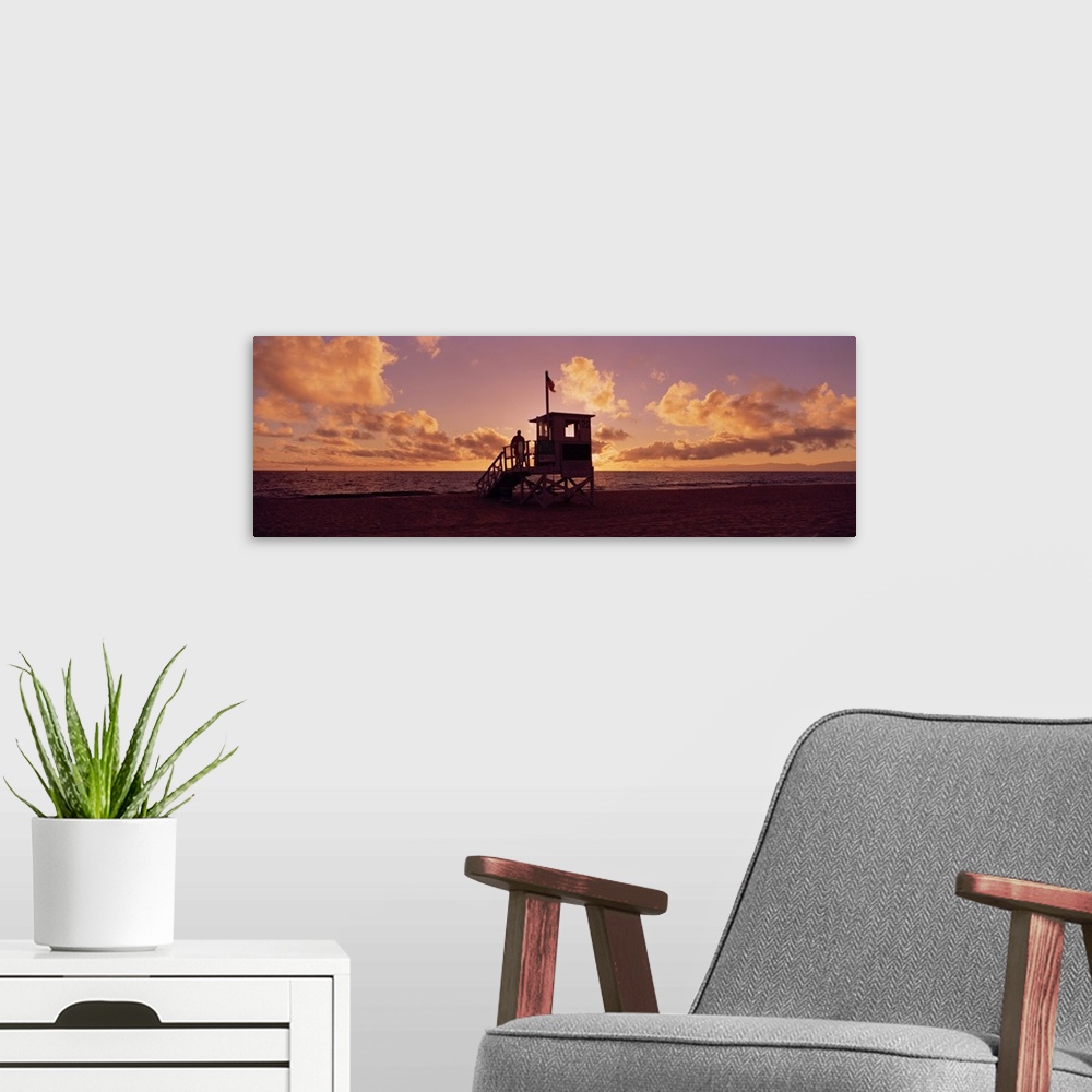 A modern room featuring Landscape photograph on a big canvas of the 22nd Street lifeguard station on Redondo Beach, silho...