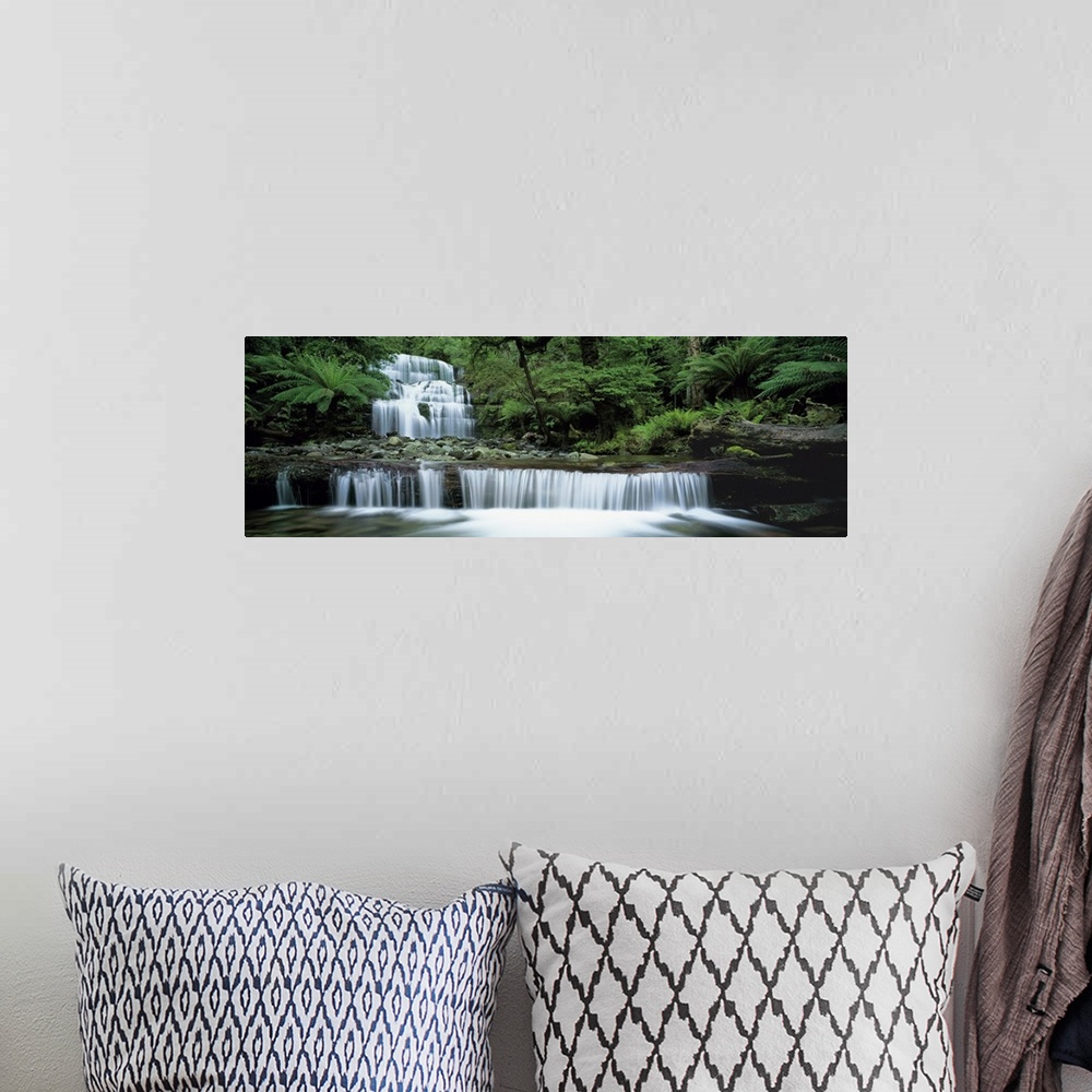 A bohemian room featuring This is a  panoramic landscape photograph of water cascading down a tiered waterfall in a tropica...