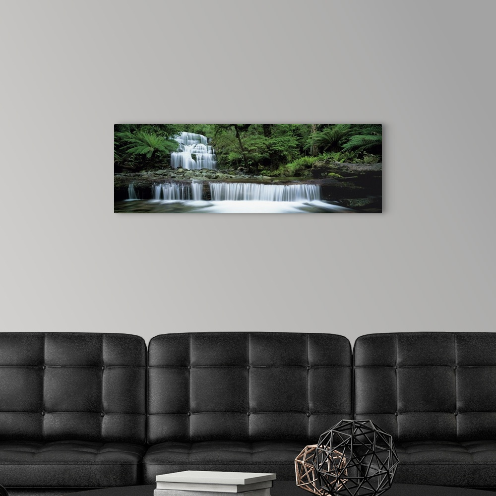 A modern room featuring This is a  panoramic landscape photograph of water cascading down a tiered waterfall in a tropica...