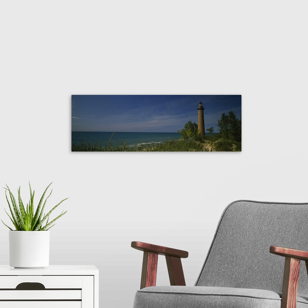 A modern room featuring Wide angle photograph of a lighthouse that is skewed to the right side of the picture and sits al...