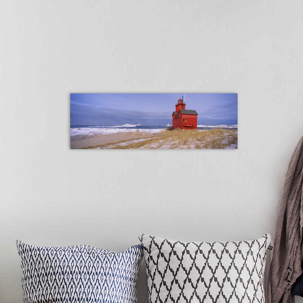 A bohemian room featuring Big horizontal photograph of the Big Red Lighthouse against a blue sky, along the coast of Lake M...