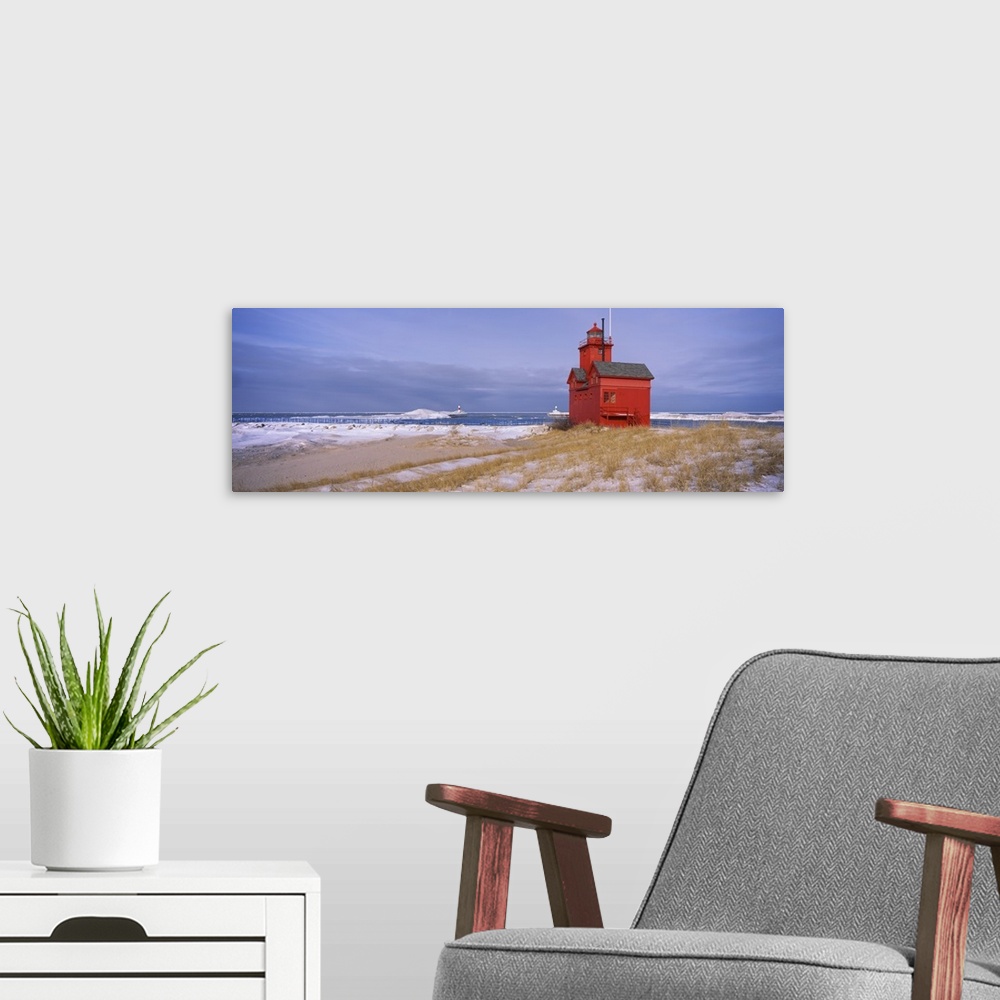 A modern room featuring Big horizontal photograph of the Big Red Lighthouse against a blue sky, along the coast of Lake M...