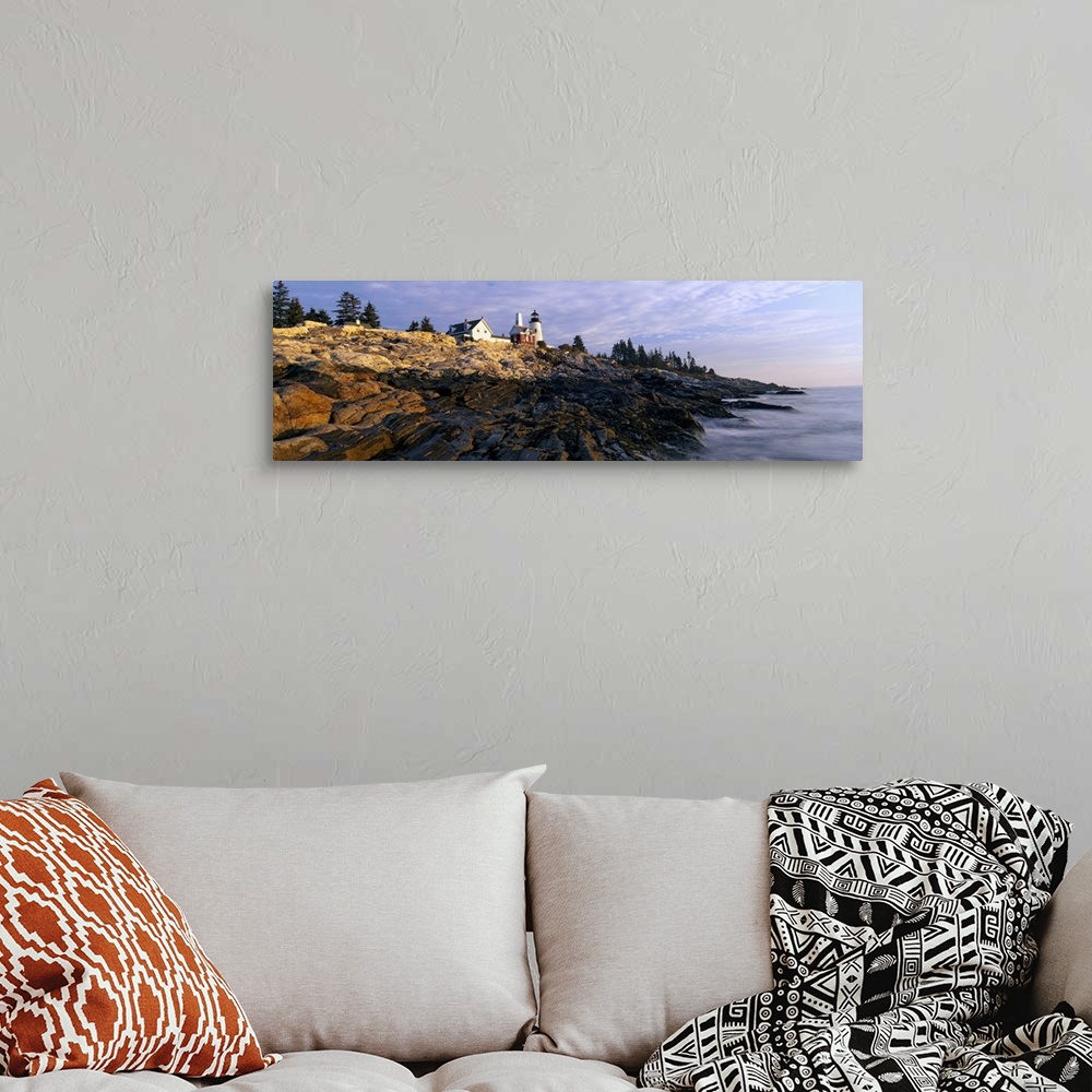A bohemian room featuring A large panoramic photograph taken from sea level and looking up at a lighthouse. Rocks take up m...