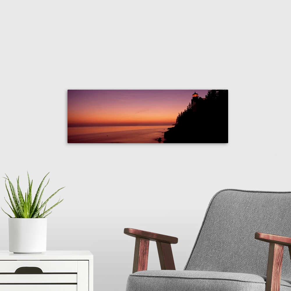 A modern room featuring Panoramic photograph taken during a sunset with a lighthouse shown on the right side of the pictu...