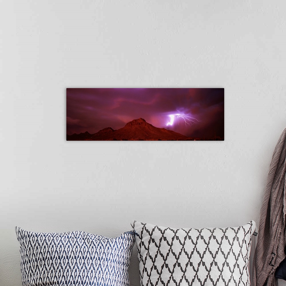 A bohemian room featuring Panoramic painting of mountain range under a dark cloudy sky with bolts of lightning.