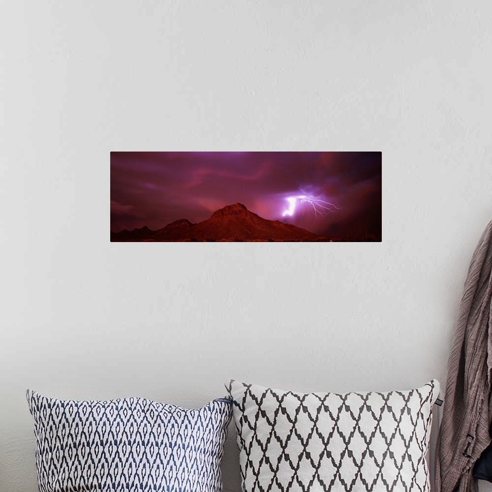 A bohemian room featuring Panoramic painting of mountain range under a dark cloudy sky with bolts of lightning.