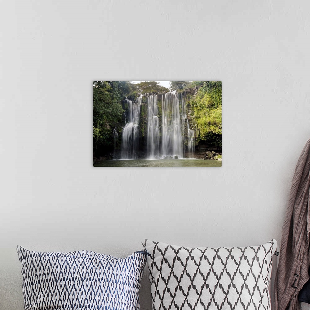 A bohemian room featuring Long exposure photograph of a waterfall over a rocky cliff in Central America with leafy jungle v...