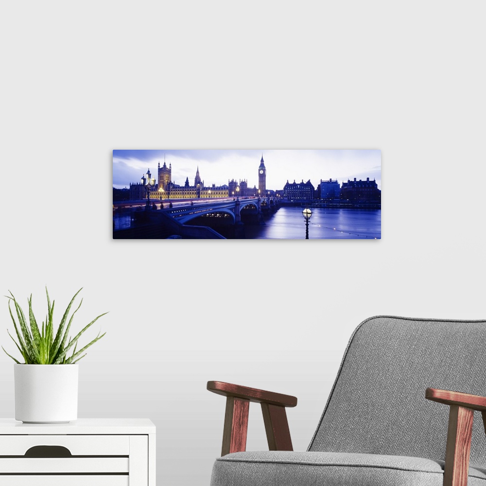 A modern room featuring London skyline with the Houses of Parliament and Big Ben. Panoramic image taken at dusk with ligh...