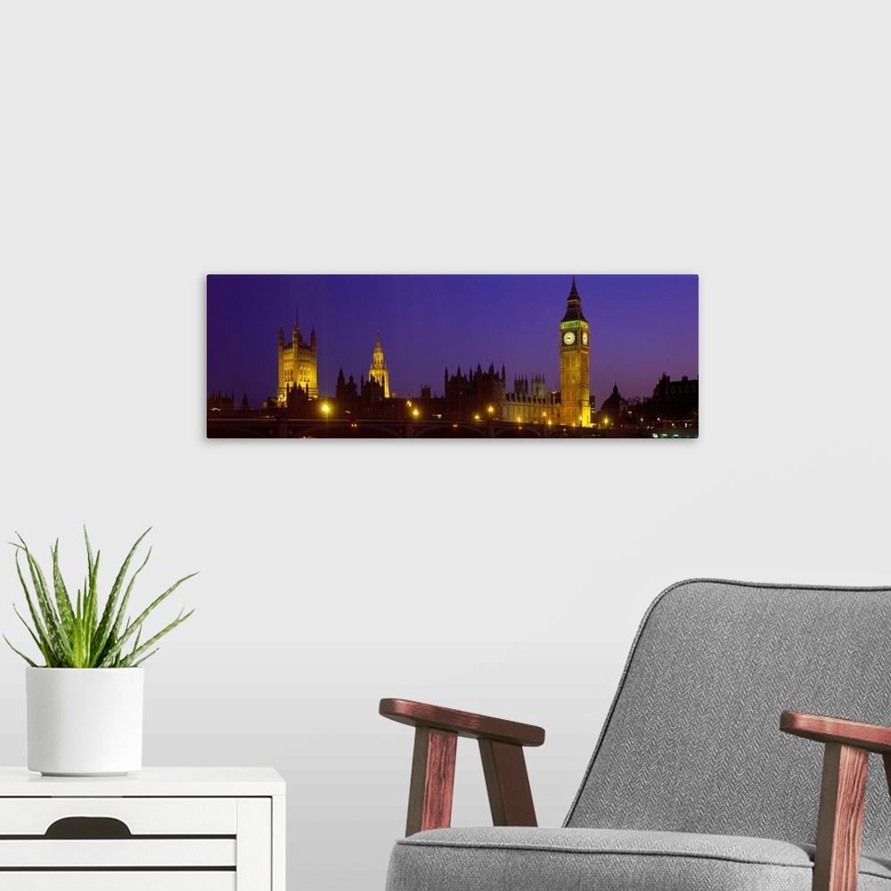 A modern room featuring London Skyline at night, Thames river in foreground also pictured Big Ben, Halls of Parliament, W...