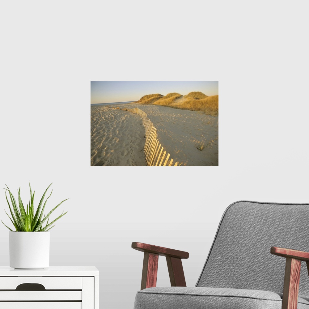 A modern room featuring Large photograph taken of a sandy beach that has a fence running through the middle of the pictur...