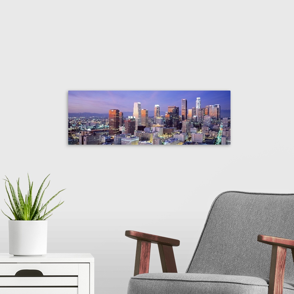 A modern room featuring This large panoramic piece shows many of the skyscrapers in downtown Los Angeles during dusk.