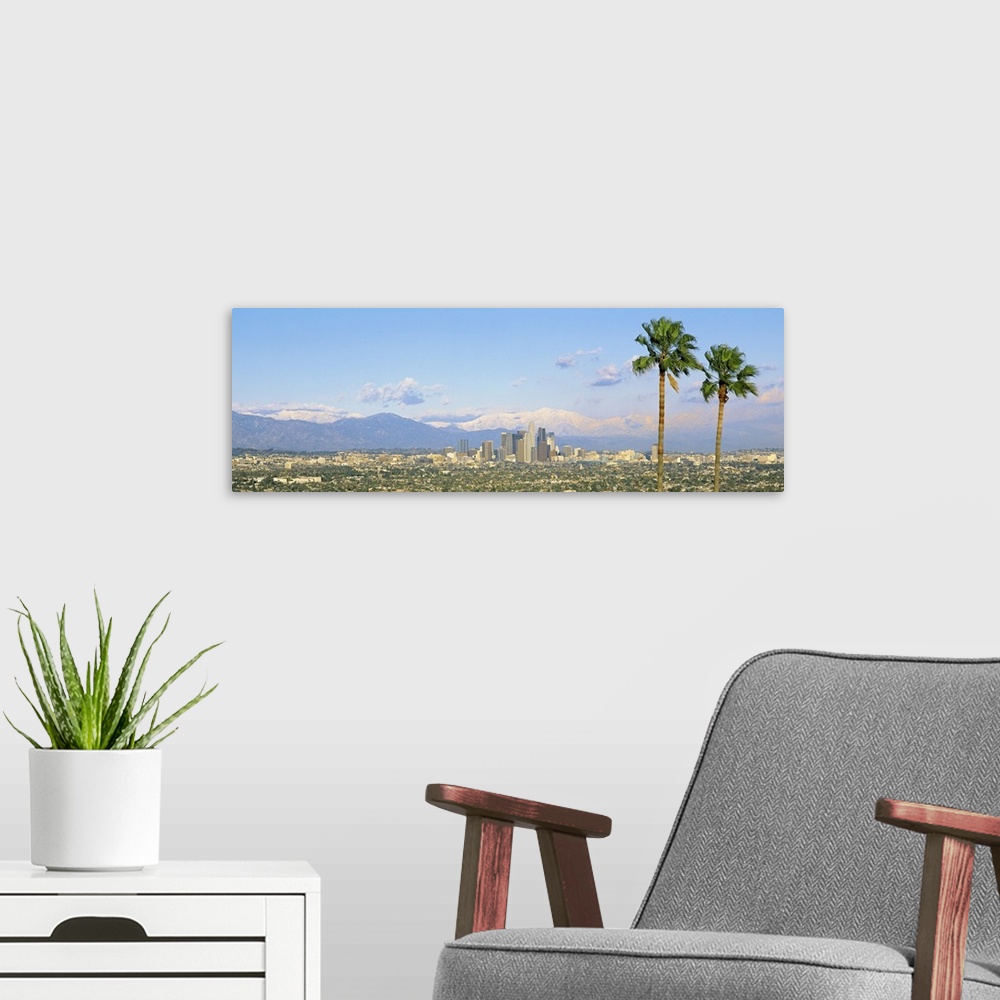 A modern room featuring A wide angle photograph taken from an aerial view of Los Angeles with two large palm trees on the...